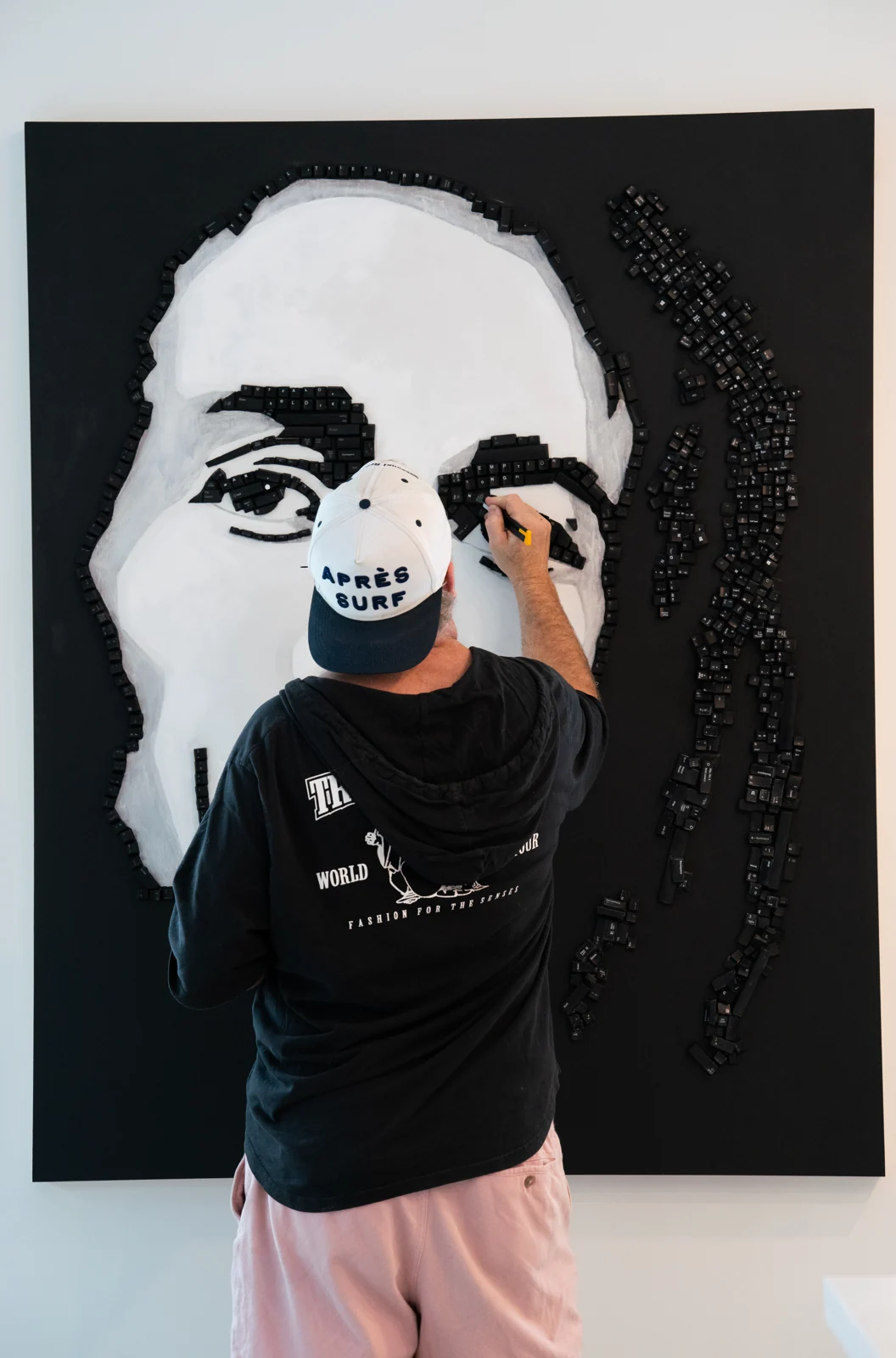 An artist working on a large black-and-white portrait.